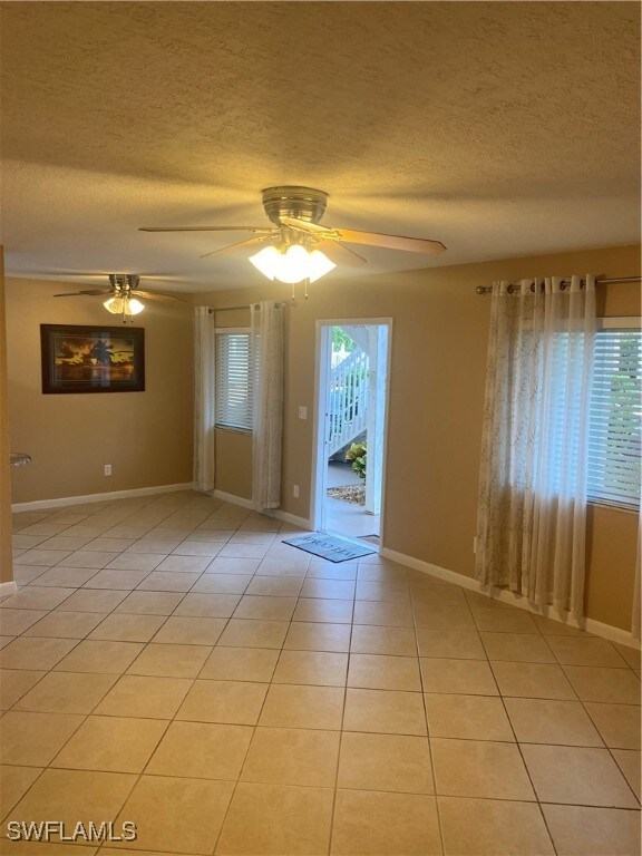 unfurnished room with a textured ceiling, a wealth of natural light, and ceiling fan