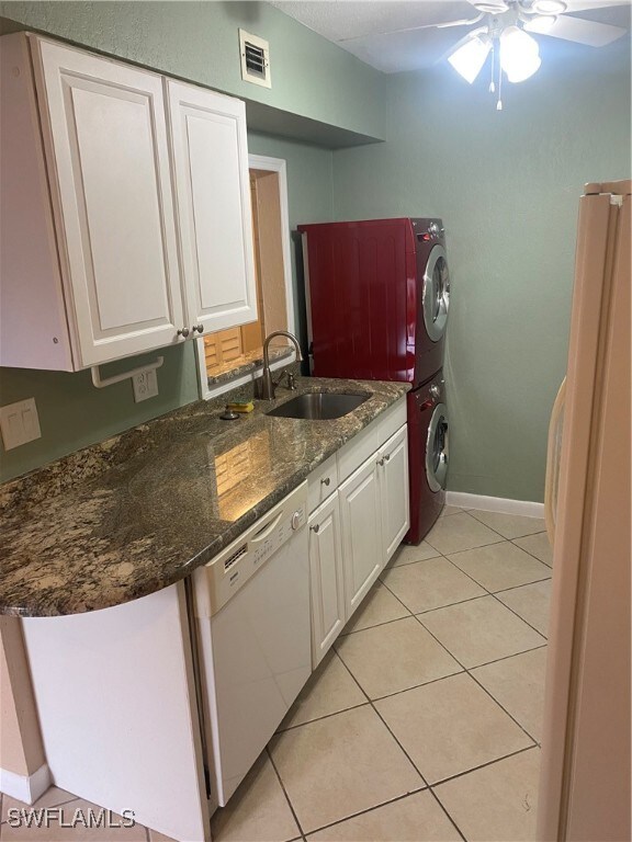 kitchen with white cabinets, white appliances, sink, ceiling fan, and stacked washer / drying machine