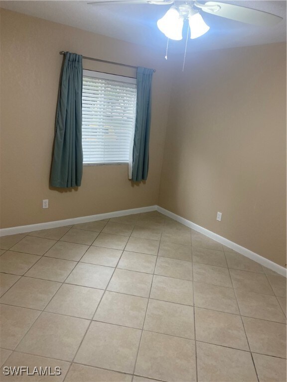 tiled spare room featuring ceiling fan