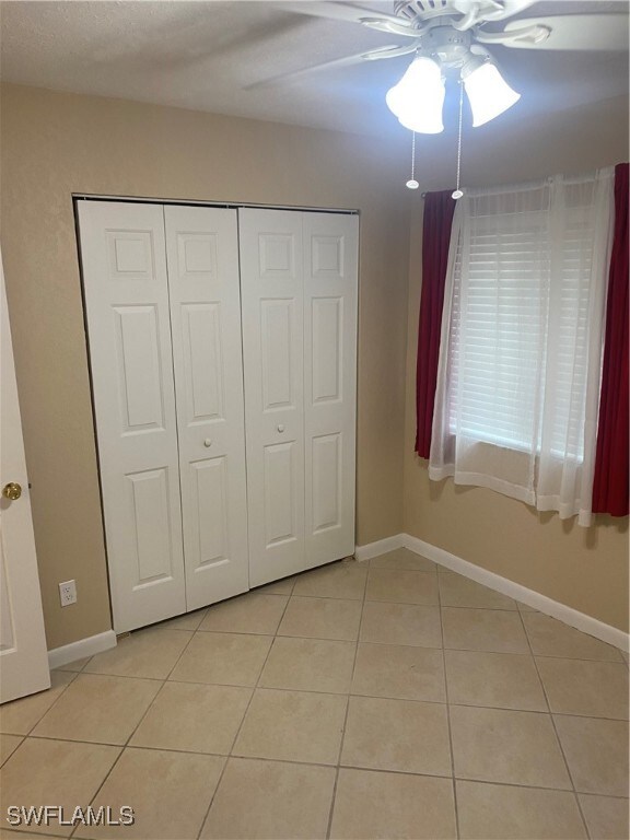 unfurnished bedroom with a closet, ceiling fan, and light tile patterned flooring