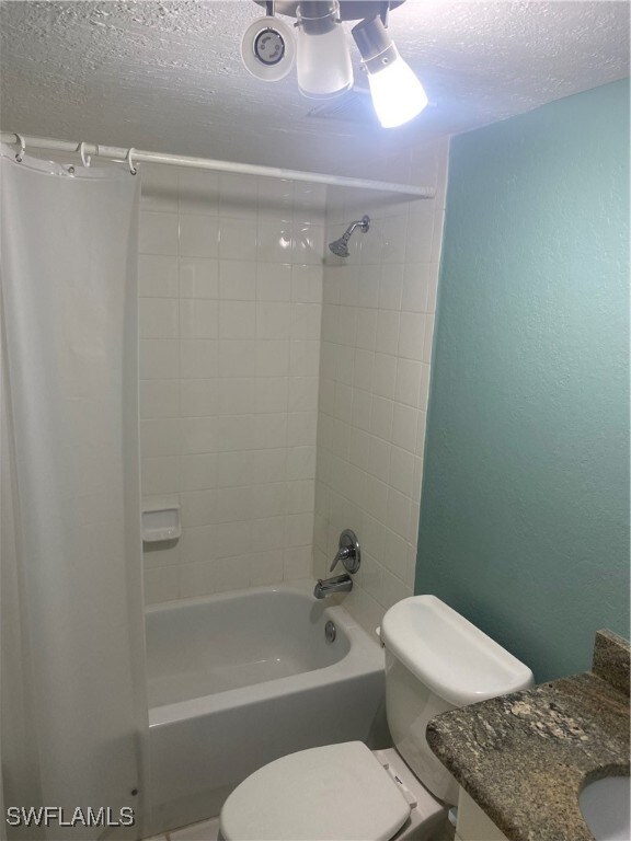 full bathroom featuring vanity, toilet, tiled shower / bath combo, and a textured ceiling