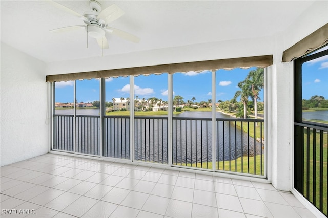 unfurnished sunroom with plenty of natural light, ceiling fan, and a water view