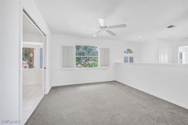 carpeted spare room featuring plenty of natural light and ceiling fan