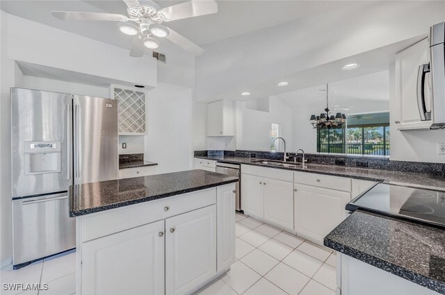 kitchen featuring a kitchen island, ceiling fan with notable chandelier, appliances with stainless steel finishes, and white cabinets