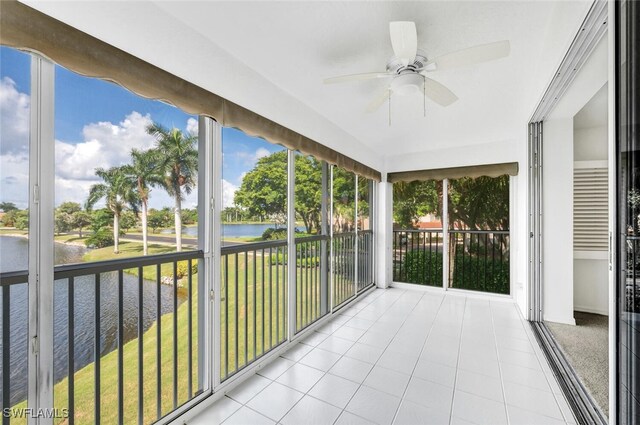 unfurnished sunroom with a healthy amount of sunlight, ceiling fan, and a water view