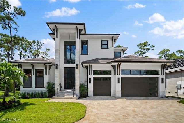 view of front facade with a garage, a front lawn, decorative driveway, and stucco siding