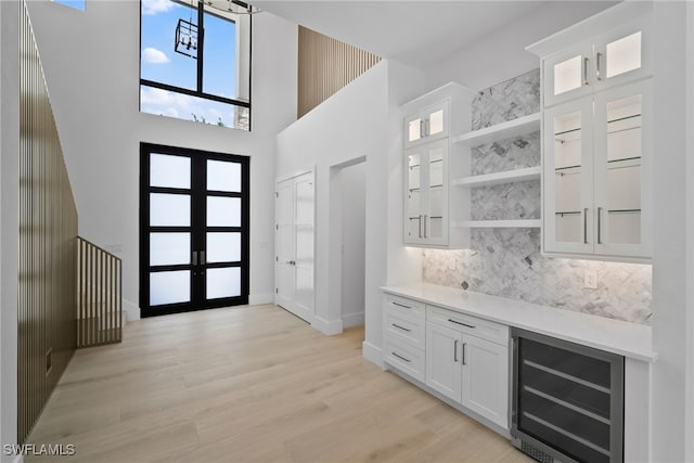 entryway featuring wine cooler, a high ceiling, and light hardwood / wood-style floors