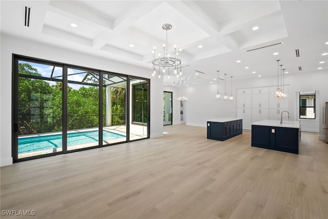 unfurnished living room with light wood finished floors, beamed ceiling, a sink, and a notable chandelier