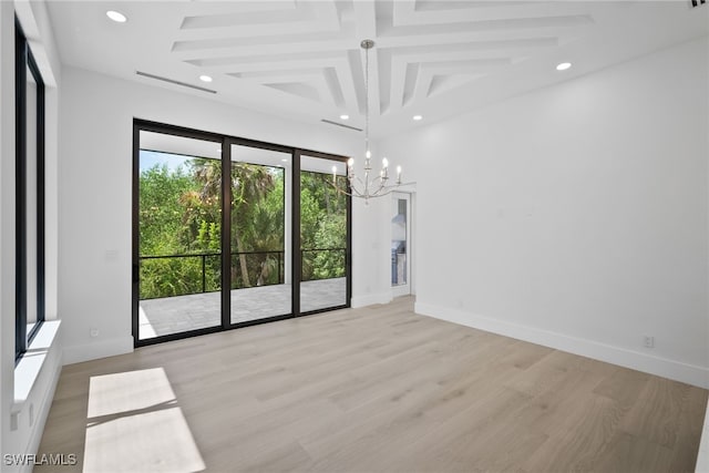 spare room with a healthy amount of sunlight, a notable chandelier, beamed ceiling, and light wood-type flooring