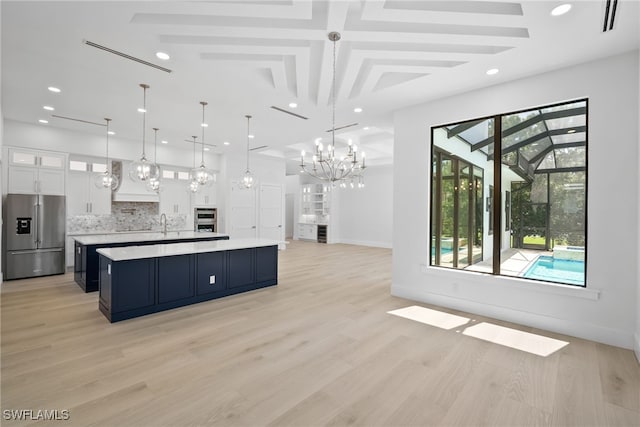 kitchen with a kitchen island, pendant lighting, appliances with stainless steel finishes, light hardwood / wood-style floors, and white cabinetry