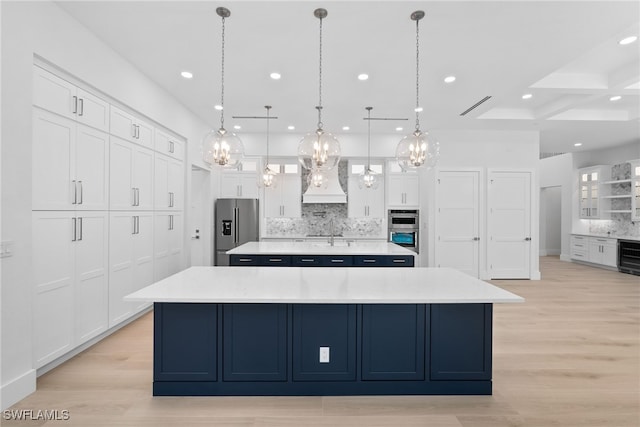 kitchen with stainless steel appliances, premium range hood, a spacious island, light countertops, and tasteful backsplash