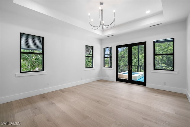 unfurnished room featuring french doors, a tray ceiling, and baseboards