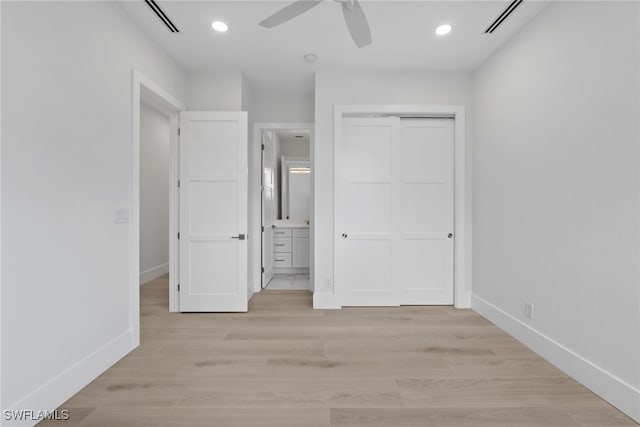 unfurnished bedroom featuring light hardwood / wood-style flooring, ceiling fan, a closet, and ensuite bath