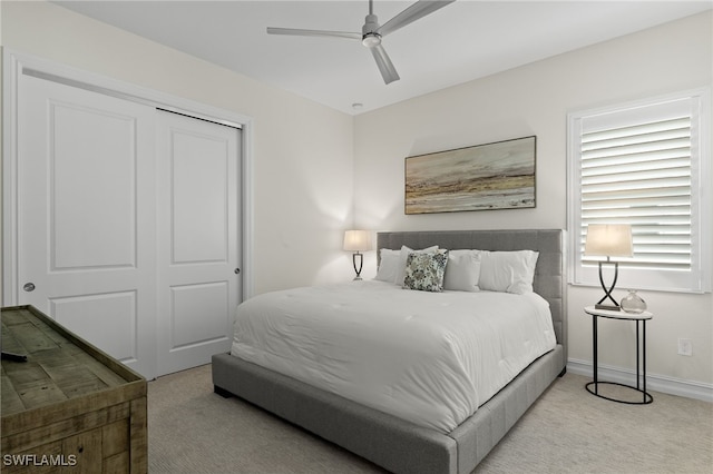 bedroom featuring ceiling fan, light carpet, and a closet