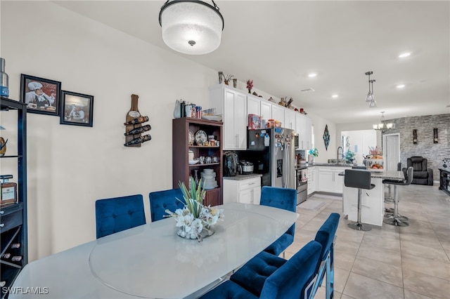 dining area with light tile patterned floors, an inviting chandelier, and sink