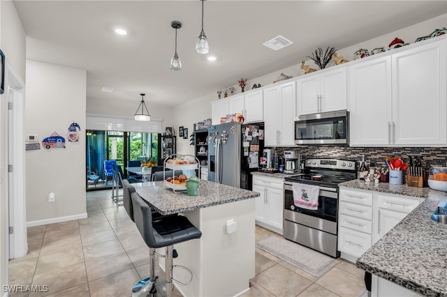 kitchen with white cabinets, decorative light fixtures, stainless steel appliances, a kitchen island, and tasteful backsplash