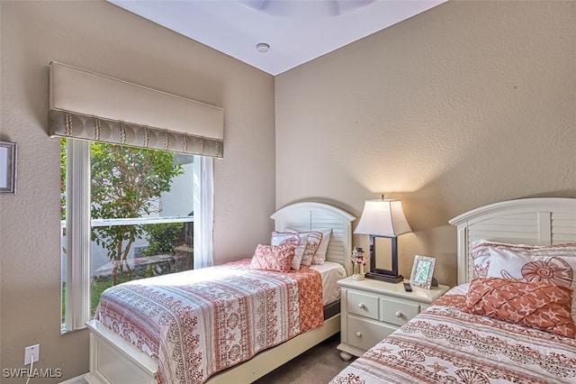 bedroom featuring a textured wall and dark colored carpet