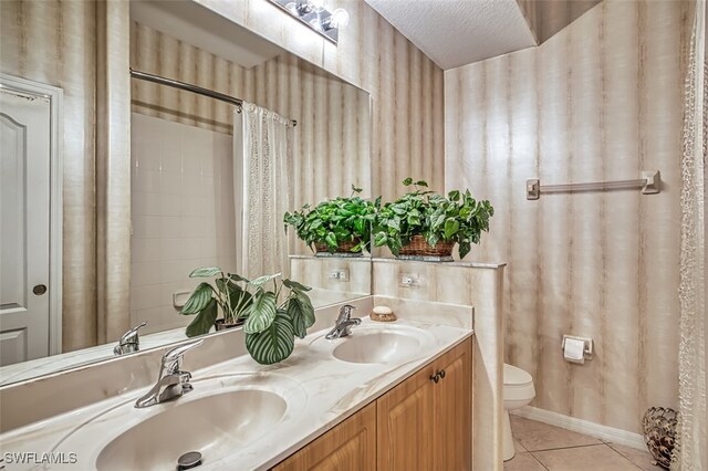 bathroom featuring toilet, tile patterned floors, vanity, a textured ceiling, and curtained shower