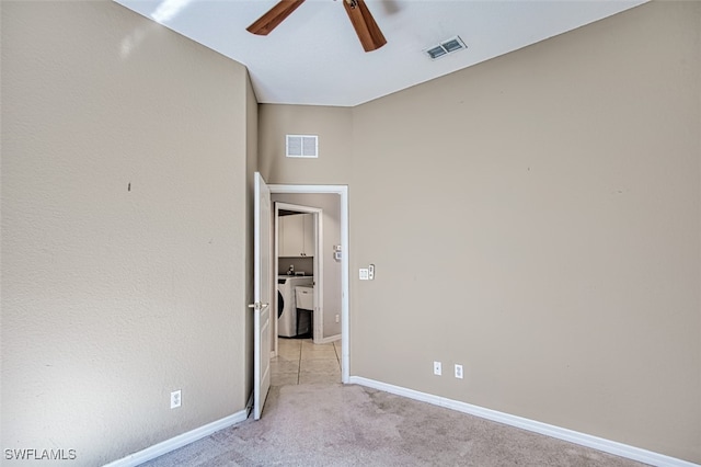 empty room with light colored carpet, washing machine and clothes dryer, and ceiling fan