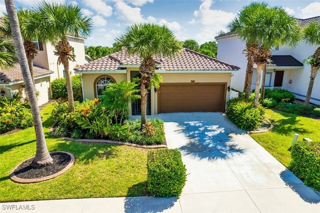 mediterranean / spanish home featuring an attached garage, stucco siding, a front lawn, and a tiled roof