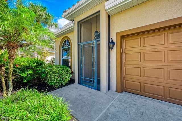 property entrance featuring a garage and stucco siding