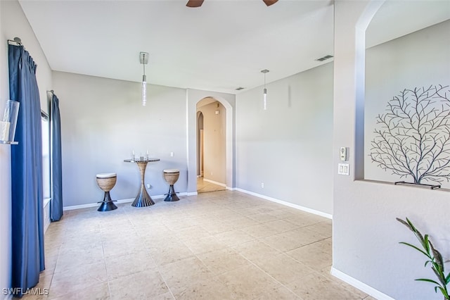 unfurnished room with ceiling fan, visible vents, arched walkways, and baseboards