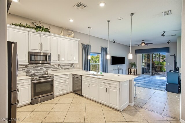 kitchen with appliances with stainless steel finishes, hanging light fixtures, kitchen peninsula, ceiling fan, and white cabinets