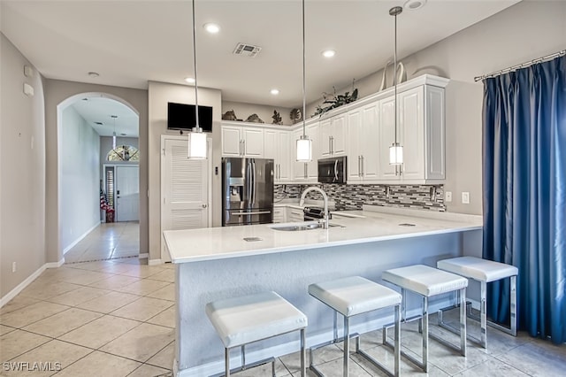 kitchen featuring white cabinets, stainless steel appliances, sink, kitchen peninsula, and a breakfast bar