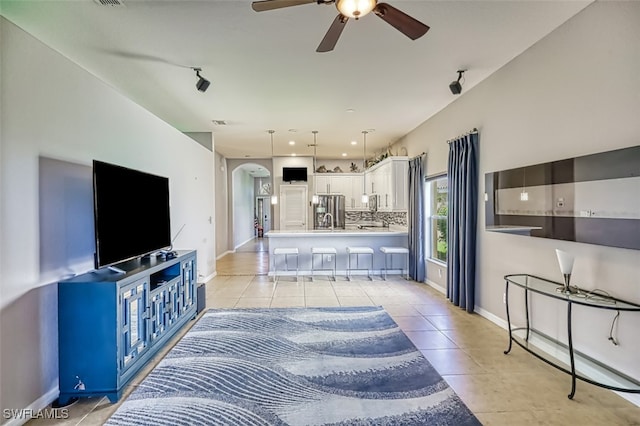 living room with baseboards, arched walkways, ceiling fan, and light tile patterned flooring