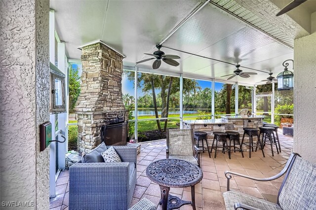 view of patio / terrace featuring an outdoor stone fireplace, ceiling fan, and a water view