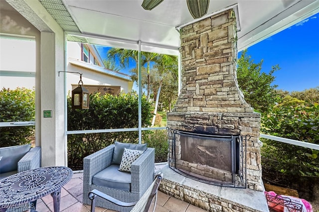 sunroom / solarium with an outdoor stone fireplace and ceiling fan