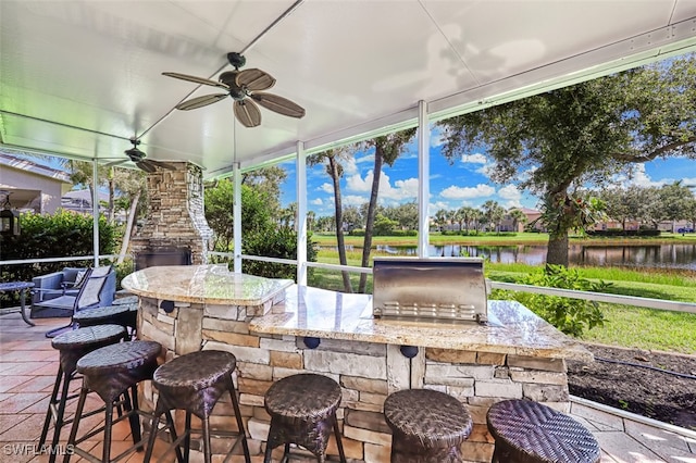 view of patio with a water view, ceiling fan, and a bar