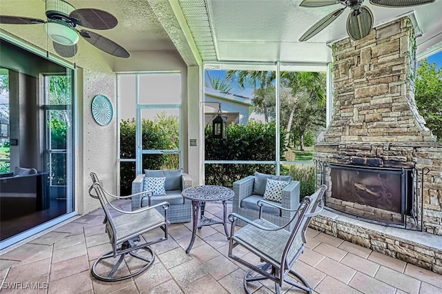 sunroom / solarium featuring an outdoor stone fireplace and ceiling fan