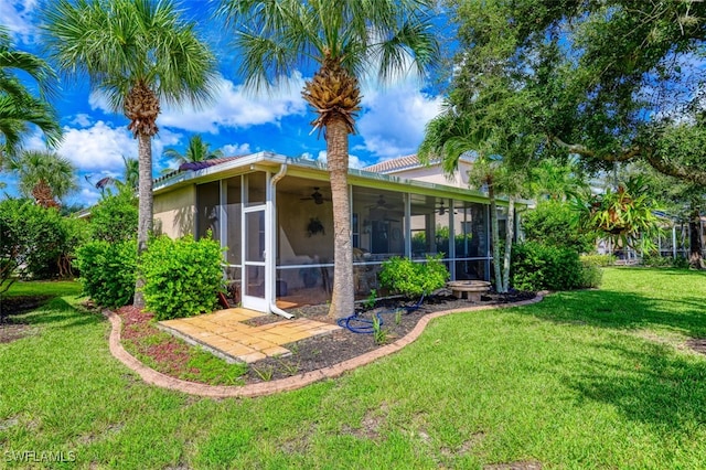 exterior space featuring a sunroom, ceiling fan, and a lawn