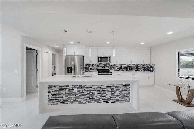 kitchen with a center island with sink, stainless steel appliances, white cabinetry, and tasteful backsplash