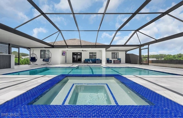 view of pool featuring glass enclosure, an in ground hot tub, and a patio