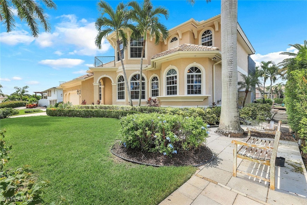 mediterranean / spanish-style house featuring a balcony, a front yard, and a garage