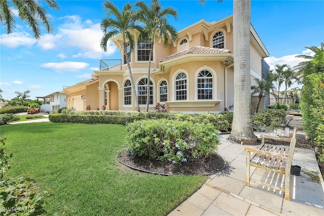 mediterranean / spanish-style house featuring a balcony, a front yard, and a garage