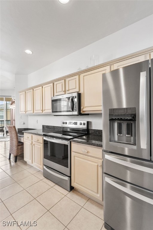 kitchen with stainless steel appliances, light tile patterned flooring, and cream cabinets