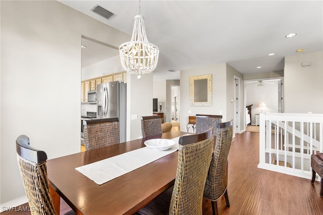 dining area with dark wood-type flooring and a notable chandelier