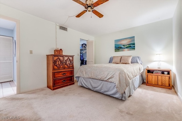 bedroom featuring light carpet, a closet, a spacious closet, and ceiling fan