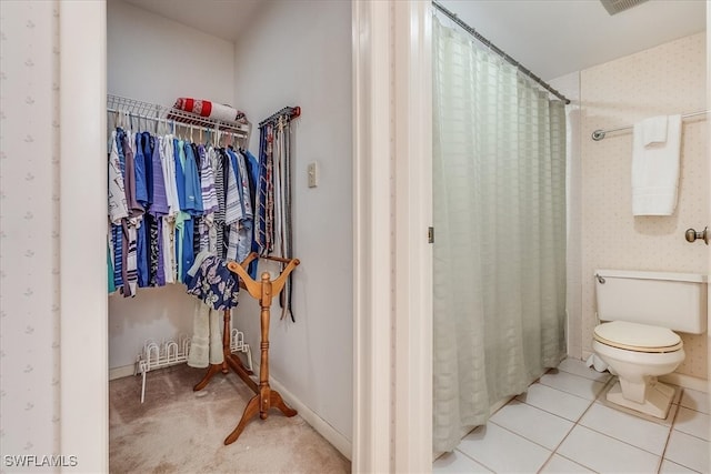 bathroom featuring toilet, curtained shower, and tile patterned flooring