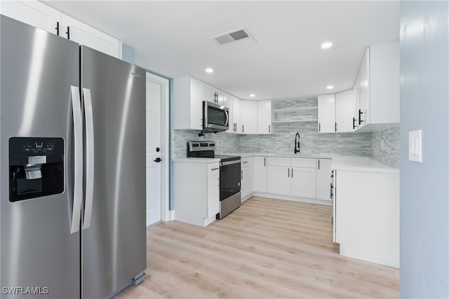 kitchen featuring sink, light hardwood / wood-style flooring, white cabinetry, stainless steel appliances, and decorative backsplash