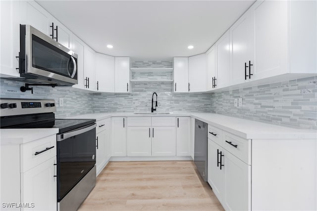 kitchen featuring white cabinetry, tasteful backsplash, stainless steel appliances, light hardwood / wood-style flooring, and sink