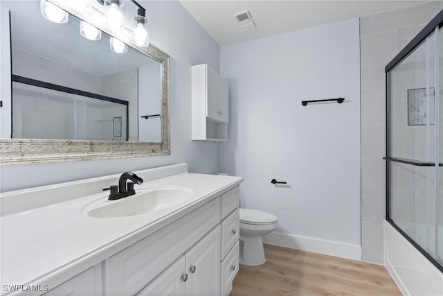 full bathroom featuring enclosed tub / shower combo, vanity, hardwood / wood-style floors, and toilet