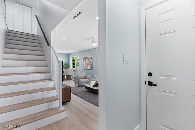 stairway with wood-type flooring and ceiling fan