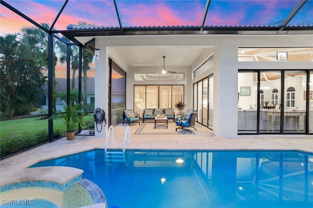 pool at dusk featuring glass enclosure, outdoor lounge area, ceiling fan, and a patio