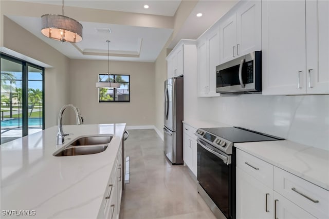 kitchen featuring sink, white cabinetry, stainless steel appliances, pendant lighting, and light stone counters