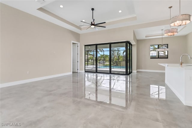 unfurnished room with ceiling fan, a raised ceiling, and sink