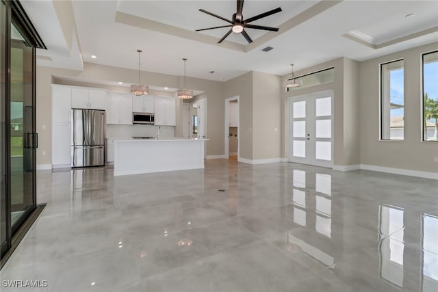 unfurnished living room featuring french doors, ceiling fan, and a raised ceiling